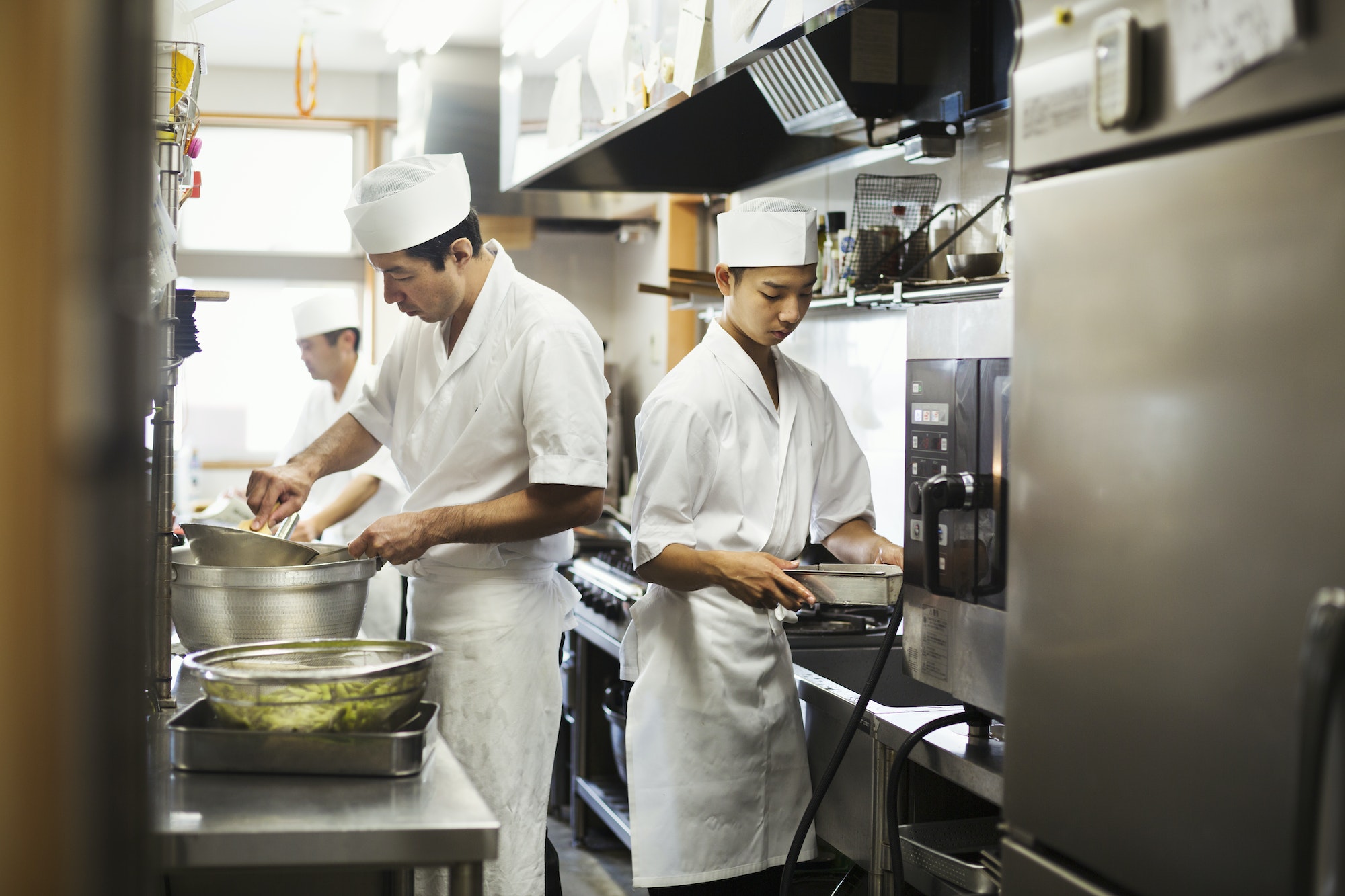 Two chefs working in the kitchen of a Japanese sushi restaurant.